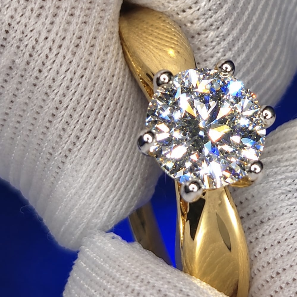 Solitaire diamond ring made to order, held in a gloved hand